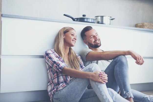 Coppia felice che discute qualcosa seduto sul pavimento della cucina