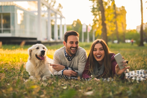 Coppia felice che fa un selfie mentre posa con un cane