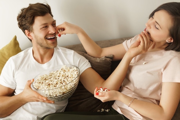 Coppia felice che mangia popcorn e guarda un film a casa