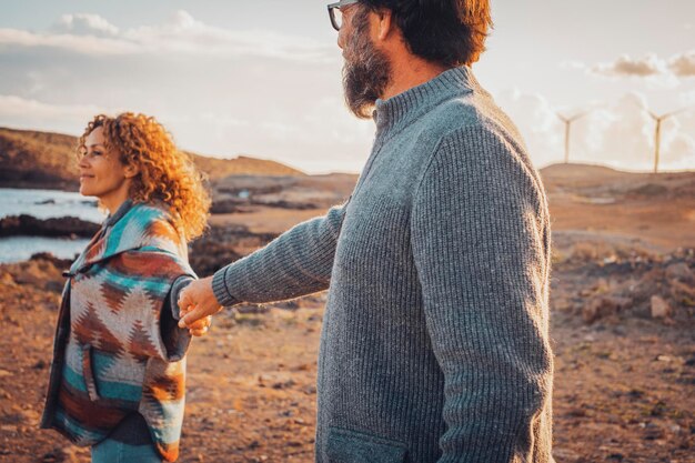 Coppia felice che si tiene per mano e cammina insieme esplorando il luogo panoramico Viaggi e relazioni romantiche Stile di vita Turista in vacanza in vacanza in campagna Uomo e donna nel tempo libero amano all'aperto