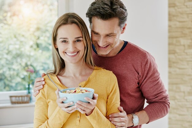 Coppia felice che tiene una ciotola con muesli a casa