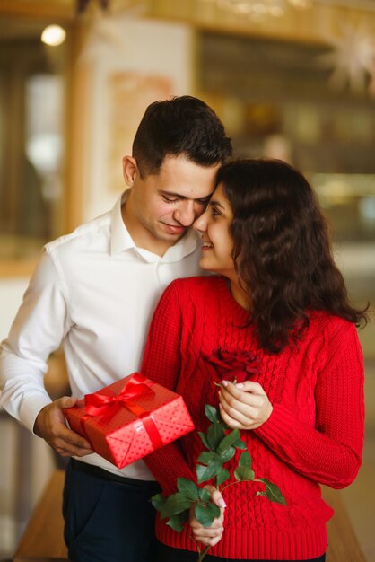 Coppia felice con abbracci regalo Confezione regalo rossa nelle mani di una coppia innamorata il giorno di San Valentino