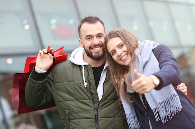 coppia felice con le borse della spesa dopo lo shopping in città sorridendo e abbracciando