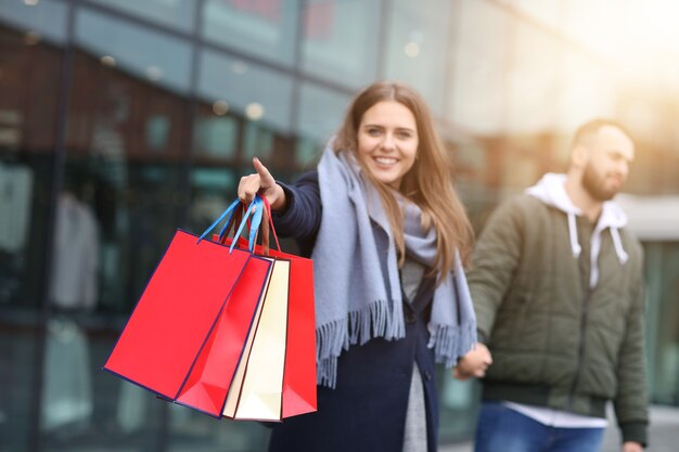 coppia felice con le borse della spesa dopo lo shopping in città sorridendo e abbracciando