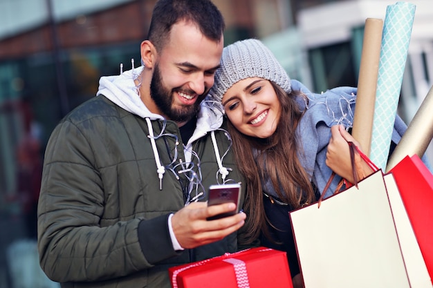 coppia felice con le borse della spesa dopo lo shopping in città sorridendo e abbracciando