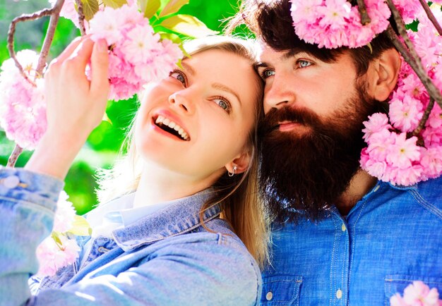 Coppia felice di stagione dei fiori di Sakura nella soleggiata giornata primaverile al giardino fiorito uomo e donna nel parco