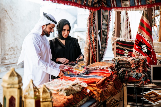 Coppia felice di trascorrere del tempo a Dubai. uomo e donna che indossano abiti tradizionali facendo shopping nella città vecchia