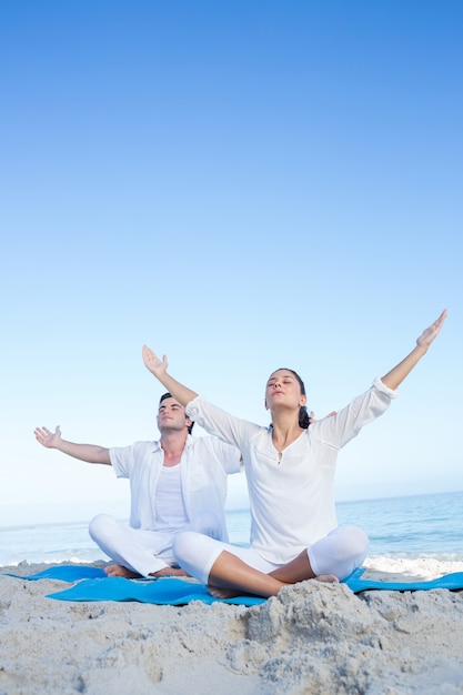 Coppia felice facendo yoga accanto all&#39;acqua