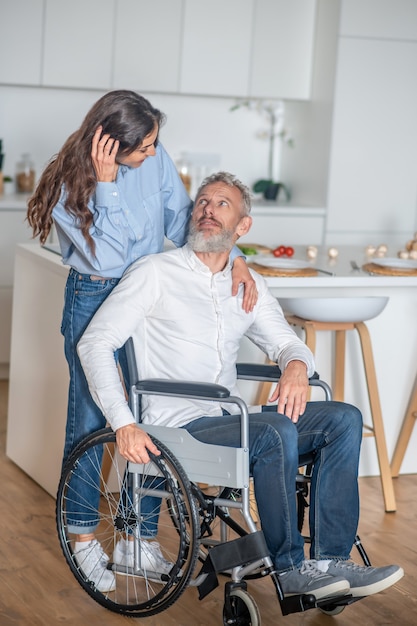 Coppia felice. Giovane donna dai capelli lunghi che sorride bene al marito disabile ed entrambi sembrano felici