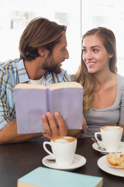 Coppia felice godendo un caffè leggendo un libro