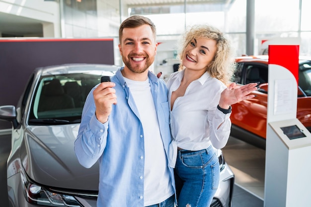 Coppia felice in concessionaria auto sullo sfondo della nuova auto