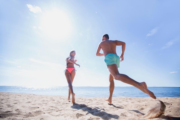 Coppia felice in esecuzione sulla spiaggia tropicale al tramonto, vacanza