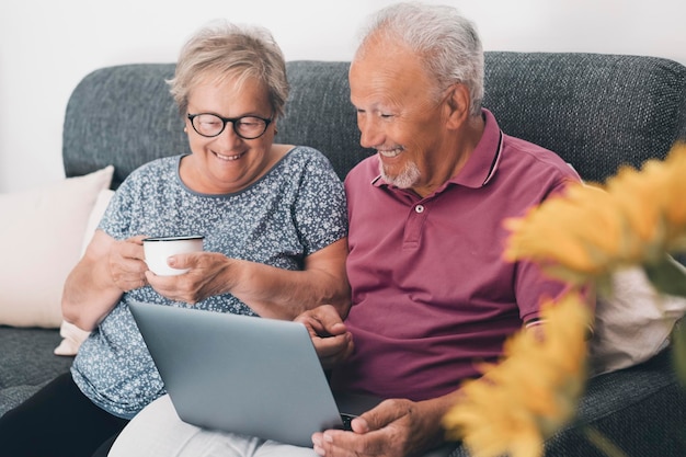 Coppia felice in pensione anziana che si abbraccia utilizzando il computer portatile insieme sorridente famiglia anziana leggendo notizie shopping online a casa persone anziane e computer o buona visione dopo il concetto di correzione laser