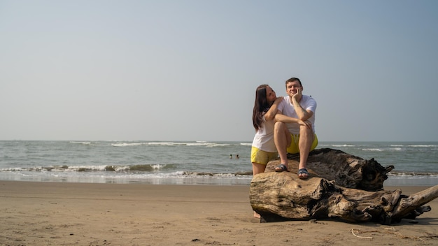 Coppia felice in posa su legni vicino al mare Coppia amorosa che si abbraccia durante l'appuntamento sulla spiaggia contro il mare ondeggiante e il cielo senza nuvole