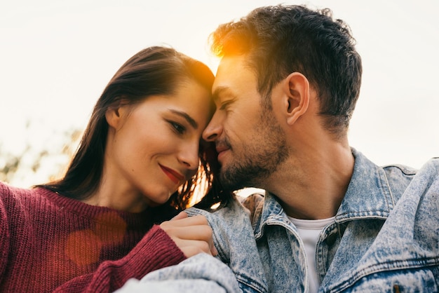 Coppia felice innamorata godendosi il sole che si abbracciano guardando con amore avendo gli occhi pieni di felicità seduti contro il cielo e lo sfondo della natura Coppia che fa un autoritratto il giorno degli appuntamenti Famiglia