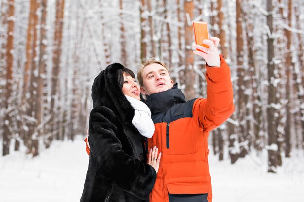 Coppia felice prendendo selfie da smartphone in inverno.