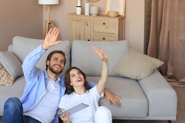 Coppia felice seduta e pianificazione di nuove decorazioni per la casa a casa con un tablet, ristrutturazione e design d'interni per la nuova casa.