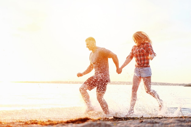 Coppia felice sulla spiaggia vacanze eseguire movimento gambe tramonto spruzzi d'acqua