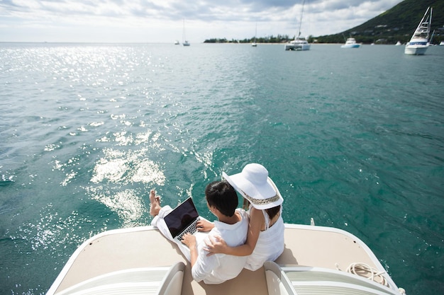 Coppia felice sullo yacht con un computer portatile