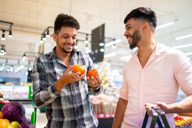 Coppia gay latinoamericana raccogliendo pomodori al supermercato