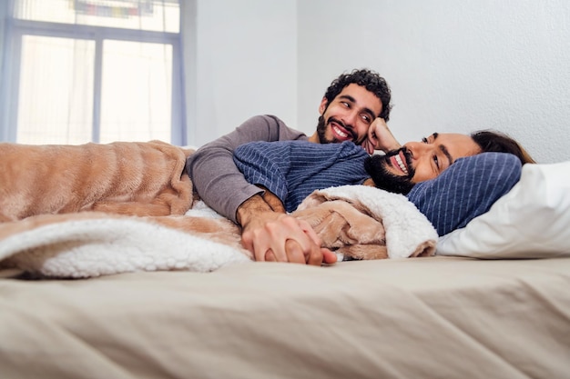 Coppia gay maschile che si rilassa sul letto con le mani giunte