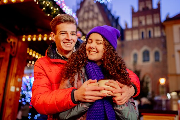 Coppia giovane con bevande sul mercatino di Natale a Wroclaw, Polonia