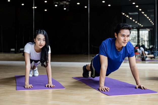 Coppia giovane con esercizio facendo yoga sul materassino yoga in palestra in palestra. Esercizio con lo yoga.