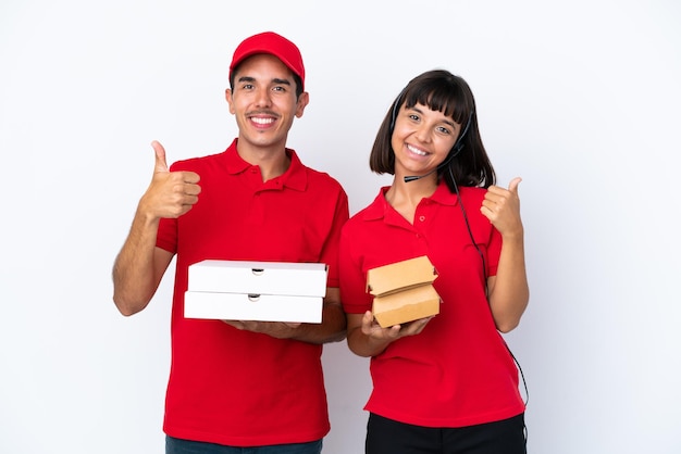 Coppia giovane consegna in possesso di pizze e hamburger isolati su sfondo bianco dando un pollice in alto gesto con entrambe le mani e sorridente