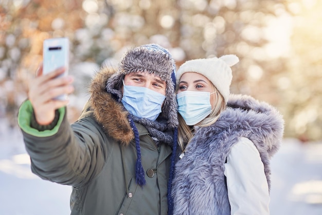 Coppia giovane divertirsi sulla neve prendendo selfie indossando maschera. Foto di alta qualità