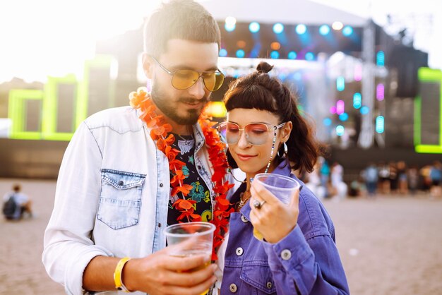 Coppia giovane e allegra al festival musicale Amici felici che bevono birra e si divertono