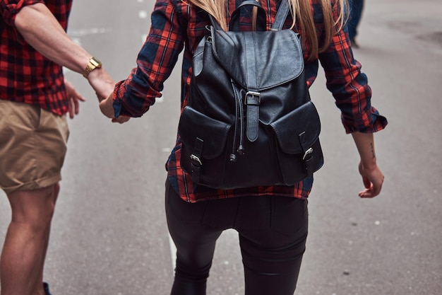 Coppia giovane hipster. Guy insegna alla sua ragazza a fare skateboard per strada nel parco.