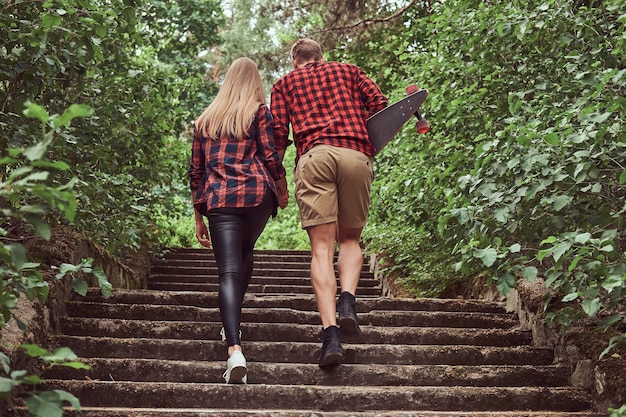 Coppia giovane hipster, passeggiata nel parco, tenendosi per mano, salendo le scale.