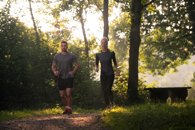 Coppia giovane in esecuzione nella foresta boscosa Area - Formazione ed esercizio per Trail Run Marathon Endurance - Fitness stile di vita sano Concept