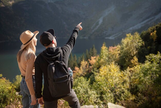 Coppia giovane in viaggio in montagna. Un uomo sta indicando sulla montagna con lo sfondo della natura