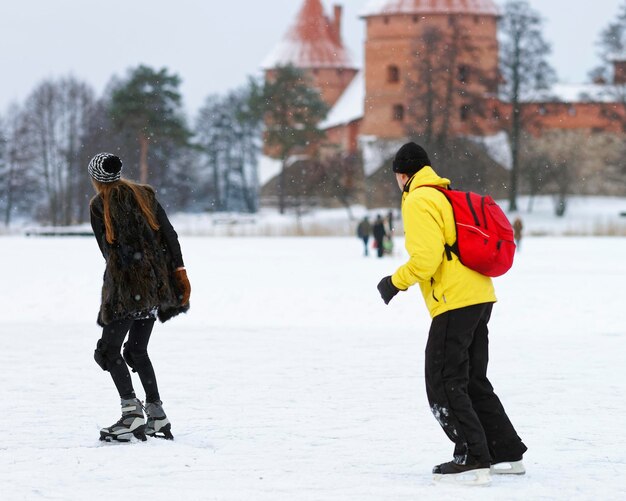 Coppia giovane Pattinaggio su ghiaccio sul lago ghiacciato in inverno Trakai. Il pattinaggio implica qualsiasi attività che consiste nel viaggiare sul ghiaccio usando i pattini. Messa a fuoco selettiva