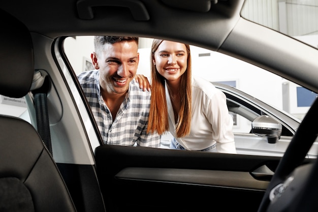 Coppia giovane scegliendo la loro nuova auto in un negozio di auto insieme