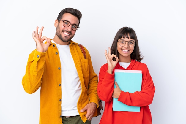 Coppia giovane studente isolato su sfondo bianco che mostra un segno giusto con le dita