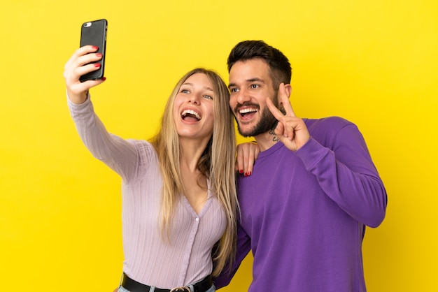 Coppia giovane su sfondo giallo isolato facendo un selfie con il cellulare