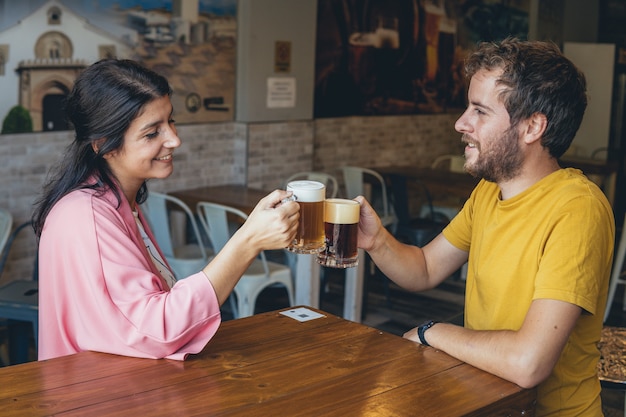 Coppia giovane su una data tostare la birra in un bar ristorante birreria