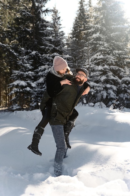 Coppia giovane sulla neve in inverno nel parco amore e concetto di vacanza coppia felice abbracciare e ridere all'aperto in inverno