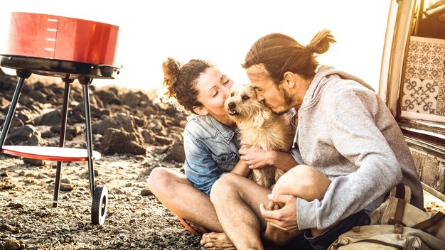 Coppia hipster e cane carino che si rilassano viaggiando sul trasporto di mini van d'epoca