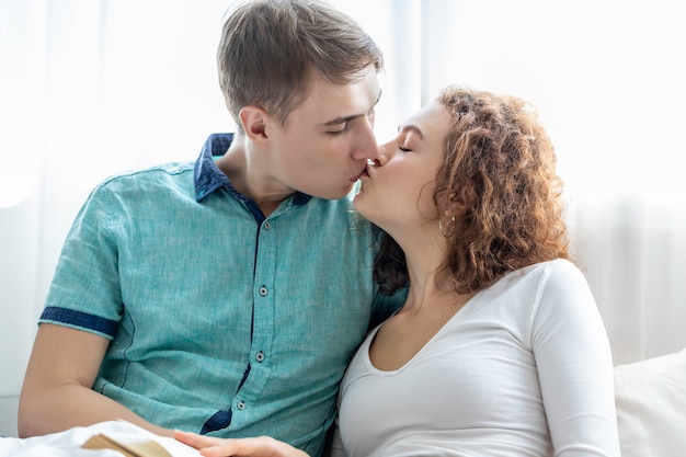 Coppia il bacio caucasico insieme mentre si trova a letto.