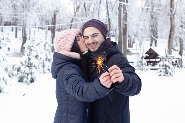 Coppia in amore baciare e tenere le scintille nel parco con la neve