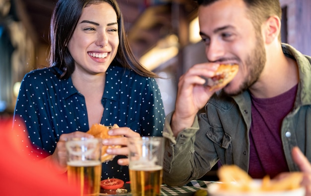 Coppia in amore divertendosi a mangiare hamburger al ristorante pub