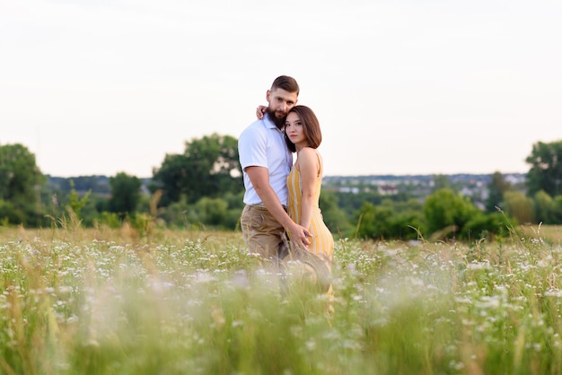 Coppia in amore in posa insieme all'aperto tra fiori di campo