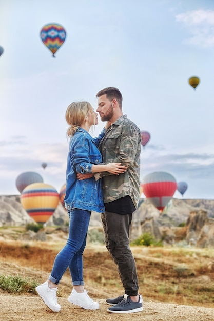 Coppia in amore si erge su sfondo di palloncini in Cappadocia.