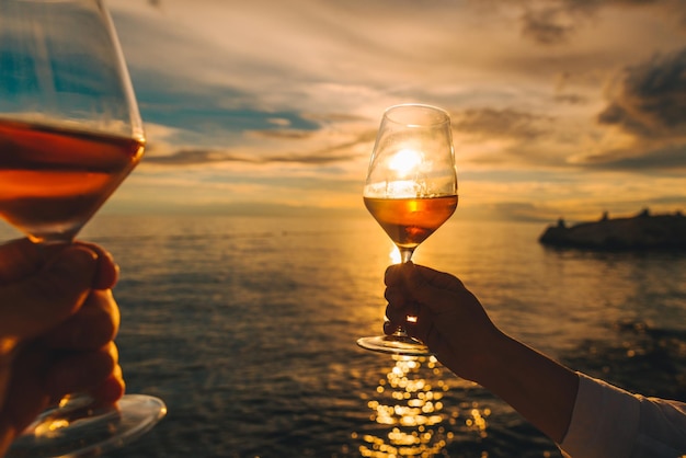 Coppia in appoggio sul tramonto sulla spiaggia del mare e bere vino