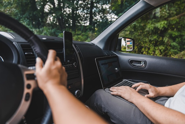 Coppia in auto uomo che lavora al computer portatile in viaggio