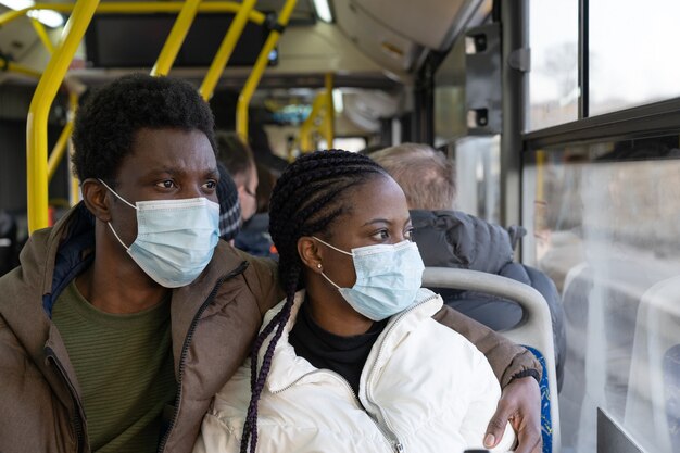 Coppia in autobus indossando maschere mentre viaggia in un nuovo uomo africano normale e una donna nei trasporti pubblici