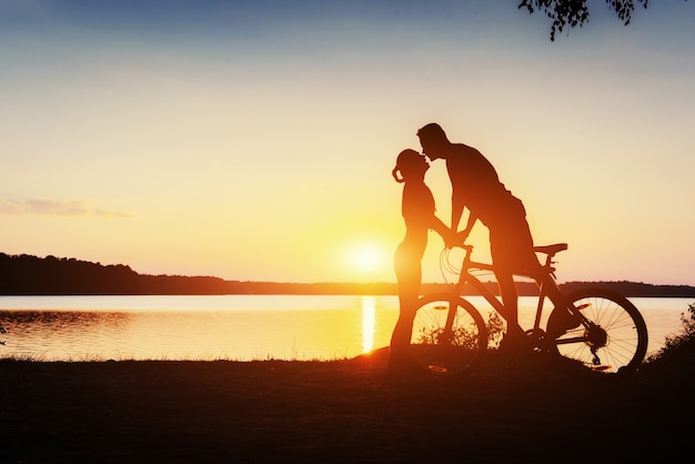 Coppia in bicicletta al tramonto sul lago